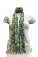A lightweight scarf with a vibrant blue, yellow, and orange floral pattern, styled with a loop at the neck