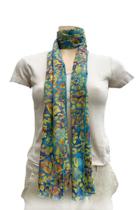 A lightweight scarf with a vibrant blue, yellow, and orange floral pattern, styled with a loop at the neck