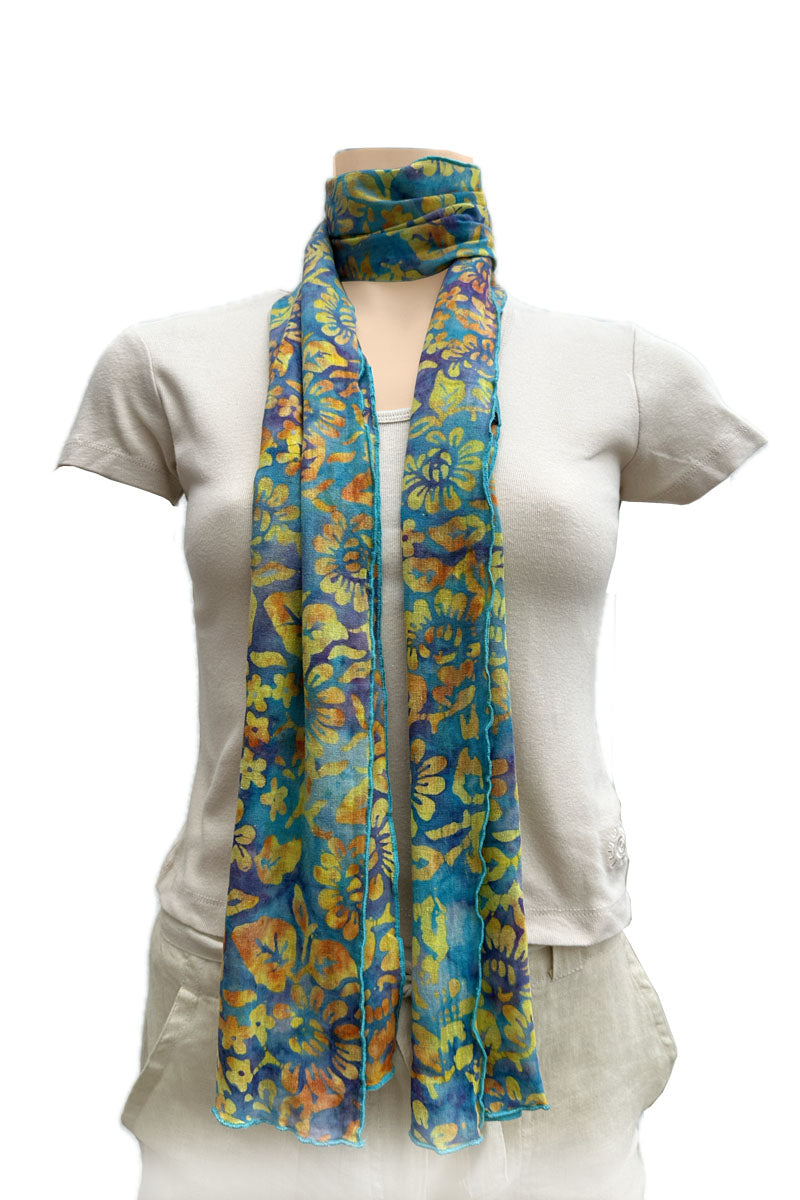 A lightweight scarf with a vibrant blue, yellow, and orange floral pattern, styled with a loop at the neck