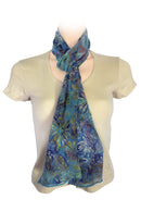 A lightweight blue and green tropical floral scarf styled in a loose knot.