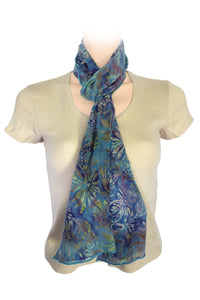 A lightweight blue and green tropical floral scarf styled in a loose knot.