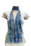 A lightweight blue scarf with a tropical floral print, styled at the nect with a loop.