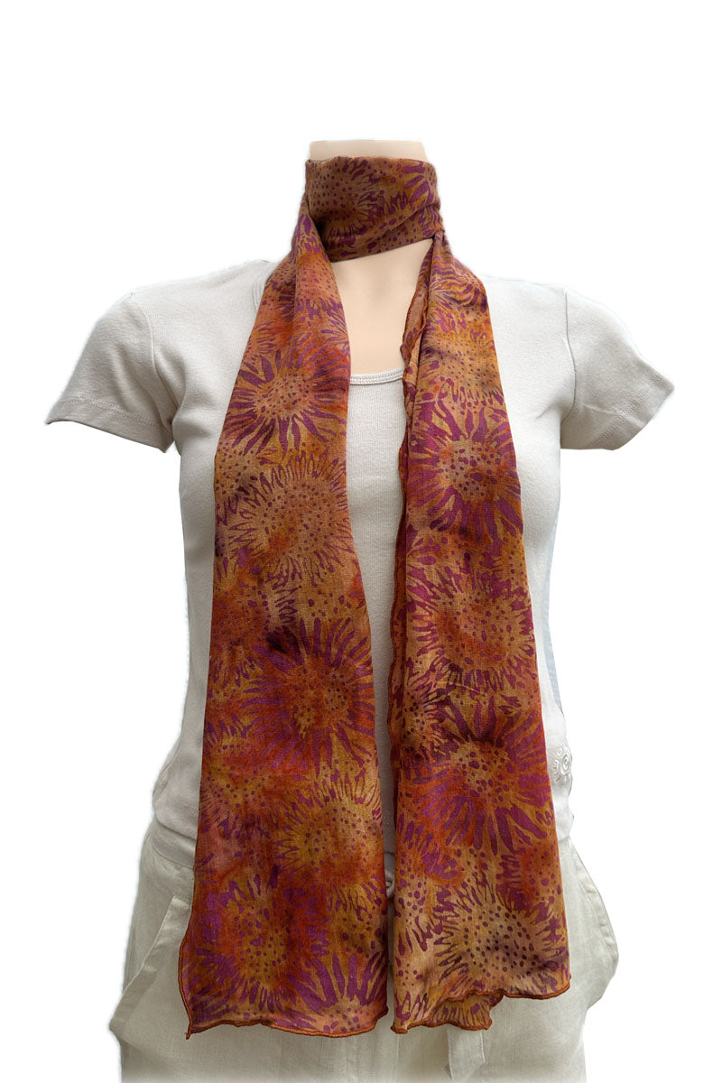 A lightweight scarf with a vibrant orange, red, and purple floral pattern, wrapped around the neck.