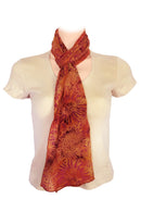 A lightweight scarf with a large sunflower pattern in shades of orange, rust, and brown.