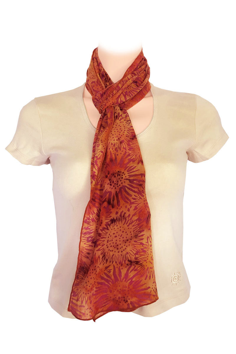 A lightweight scarf with a large sunflower pattern in shades of orange, rust, and brown.