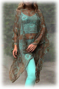 Woman wearing a floral patterned kimono-style garment over a turquoise outfit with a blurred background.