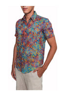 A short-sleeved, button-up shirt with a handprint batik pattern in a bright colors, displayed on a model.